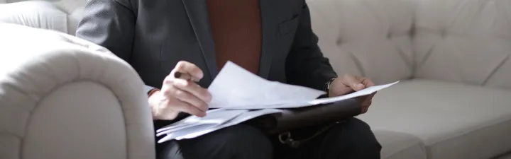 Revisjonsplikt: Person som sitter og overgår et dokument i en sofa 