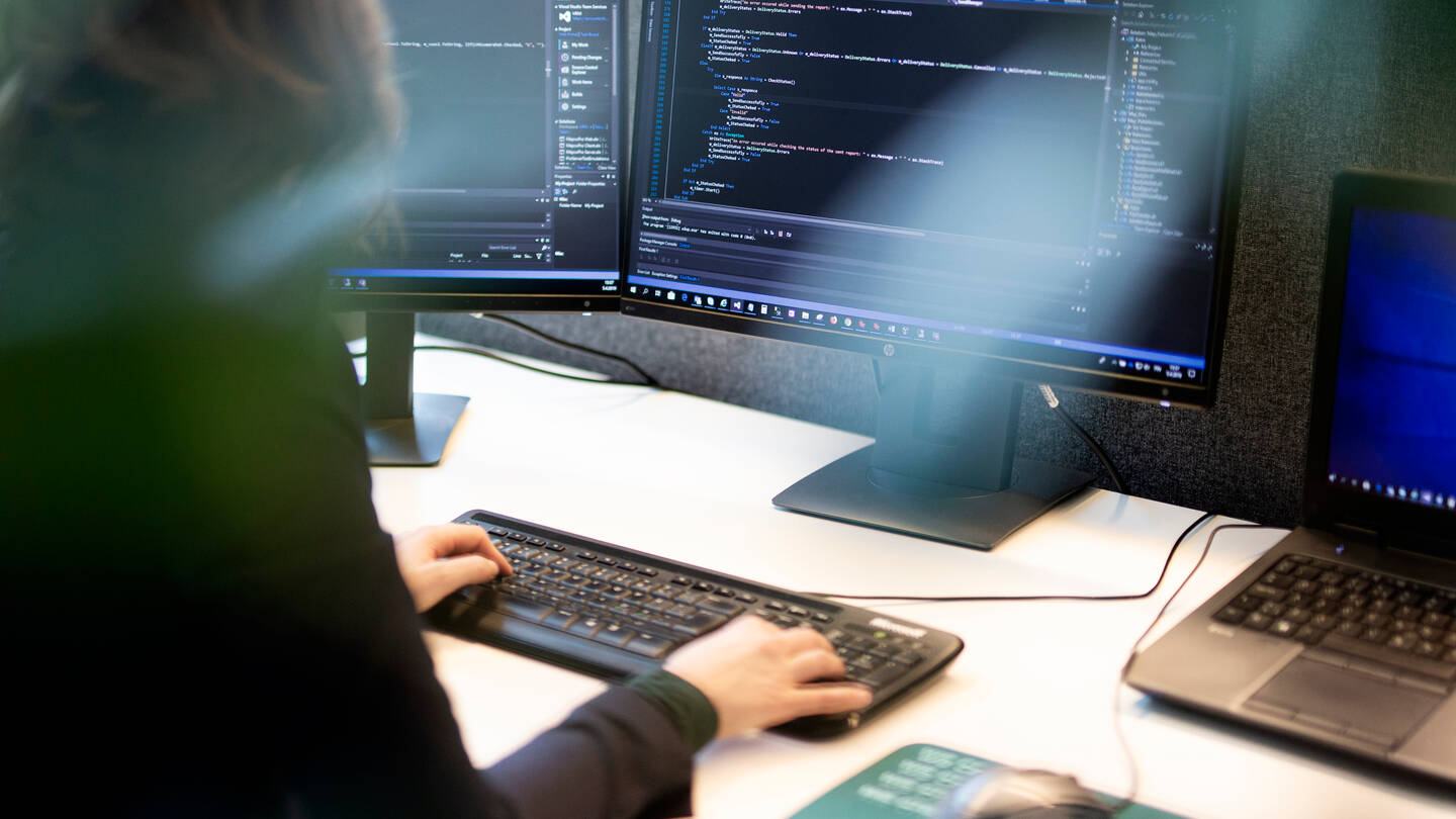 Dame som sitter foran en pc og koder