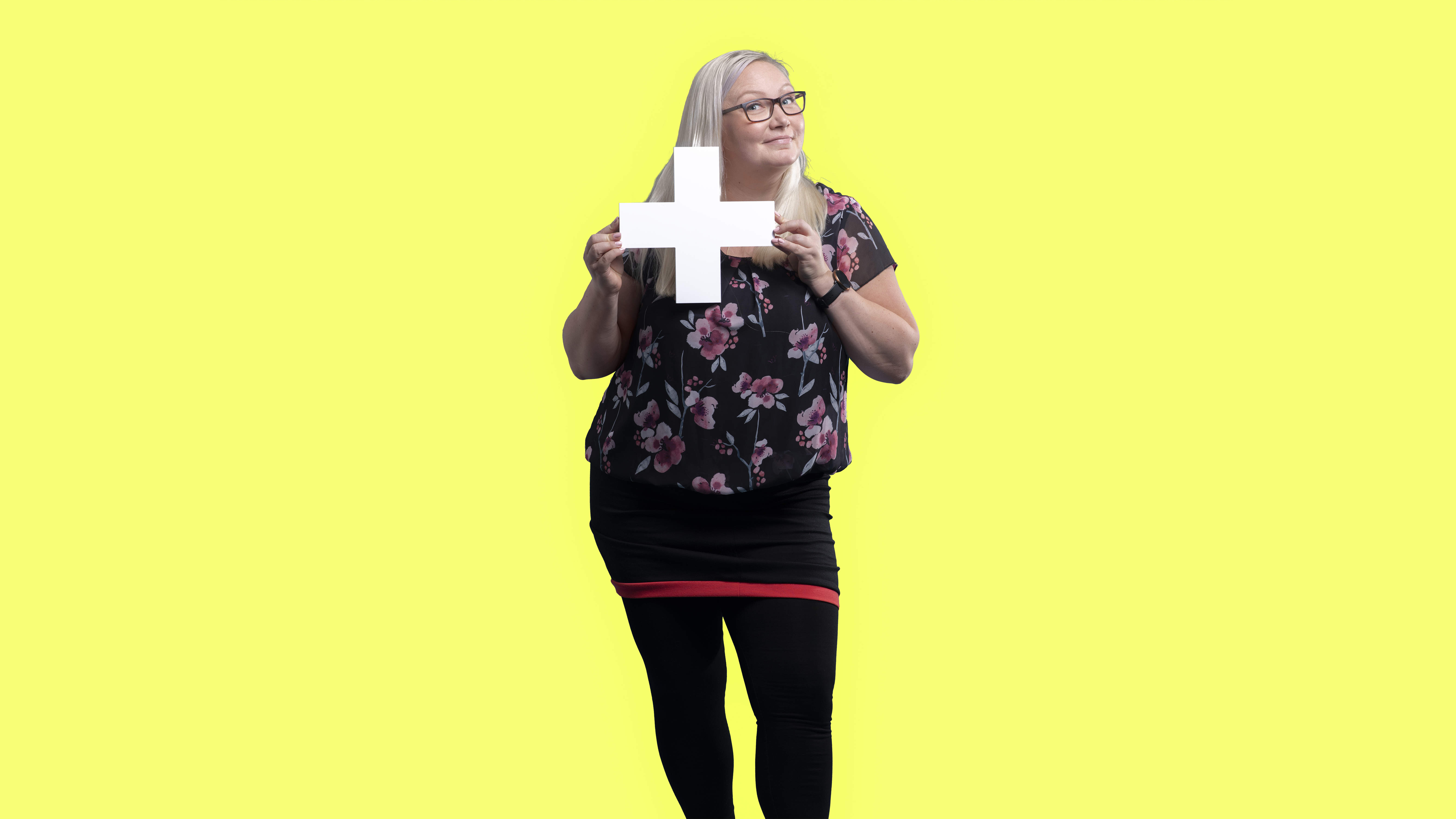 woman holding +-sign in yellow background