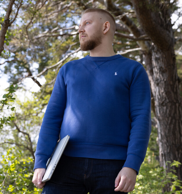 Mann med laptop ute i skogen