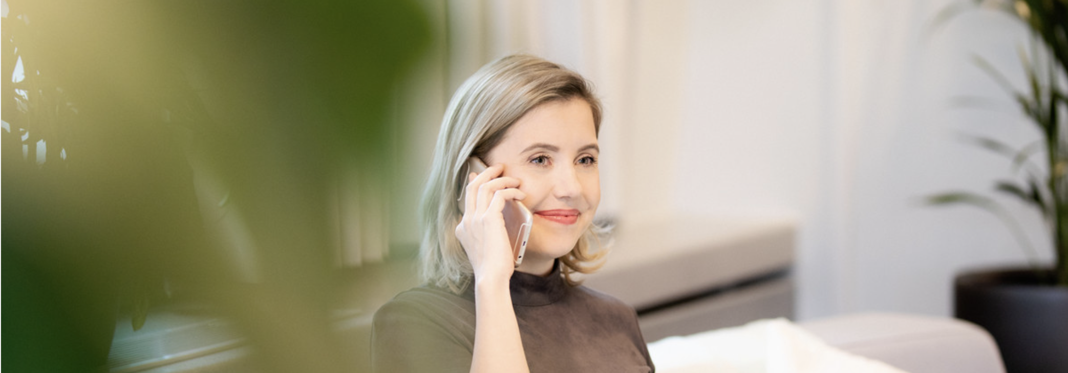 Dame snakker i telefon i et åpent landskap med masse planter