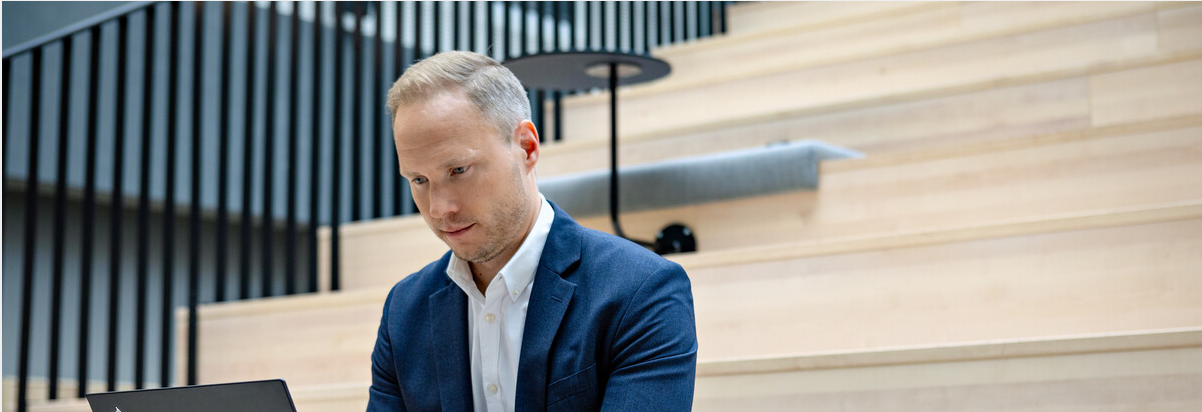 Mann fokuser med pc sitter i et åpent auditorium