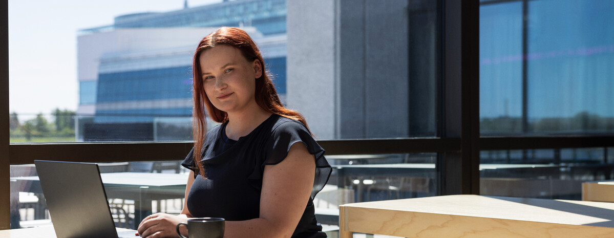 Kvinne i sola som sitter på pcen