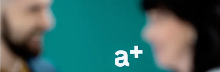 a+ logo i fokus to kollegaer i uklart fokus
