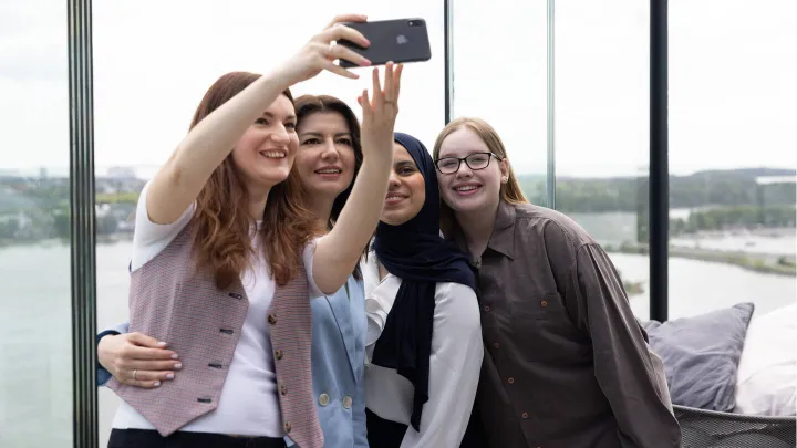 Kvinner som står sammen i en klynge smilende og tar en selfie