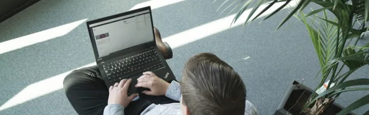 Mann med laptop sitter i en stol med planter rundt