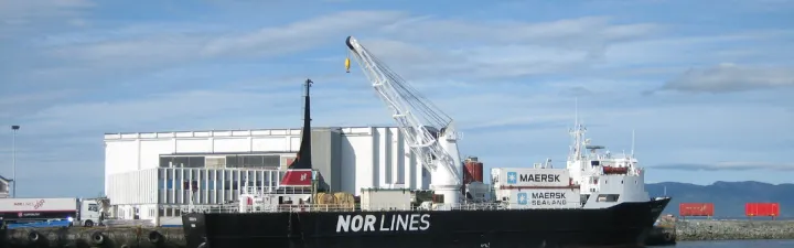 Skip legger til havn i Nordkyn med blå himmel i bakgrunnen