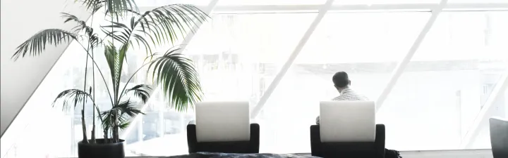 Office space with glass ceiling and a man sitting in a comfy chair with this computer