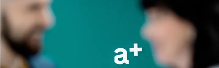 a+ logo i fokus to kollegaer i uklart fokus
