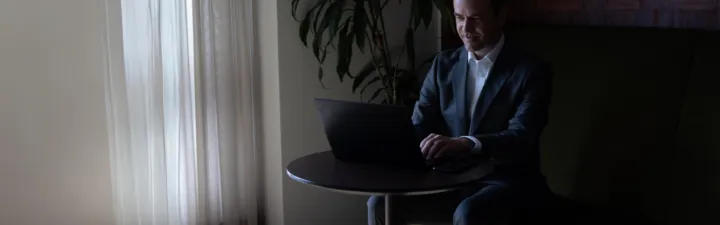 Mann med laptop sitter ved et bord og jobber 